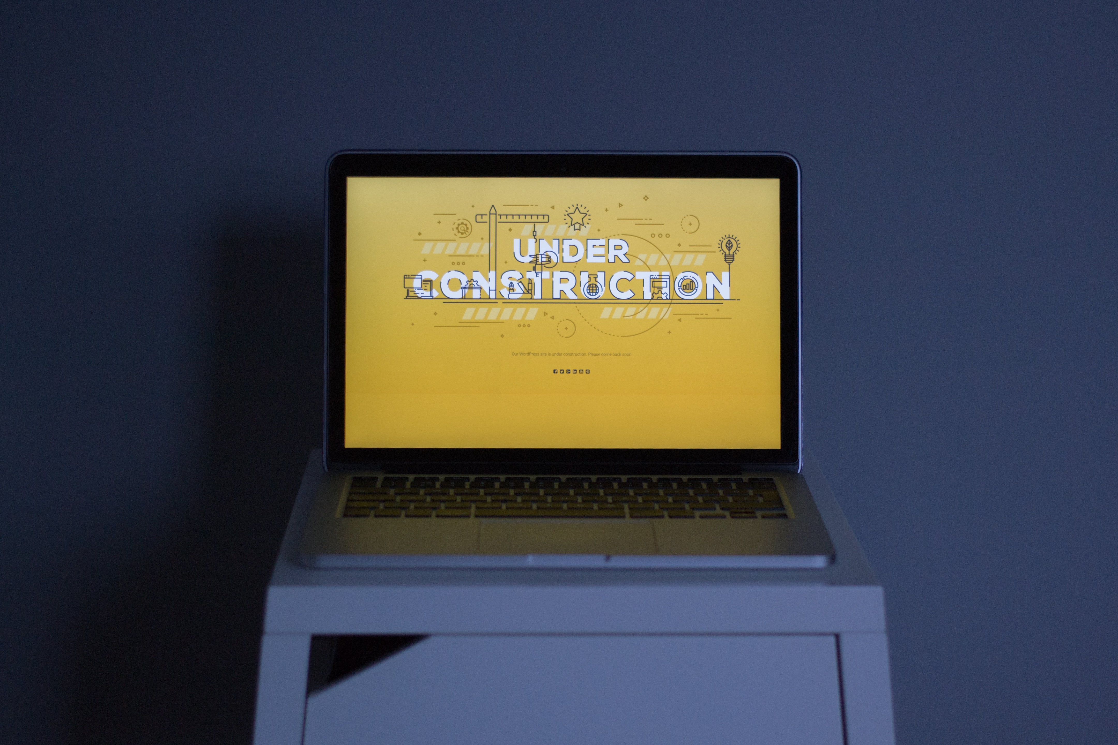 image of computer with words under construction on screen with yellow background